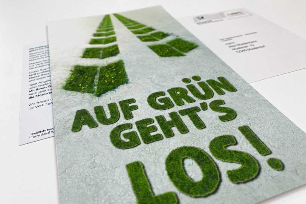 Werbematerial mit der Aufschrift „Auf Grün geht's los!“ in einer grünen, grasartigen Schrift auf grauem Hintergrund.