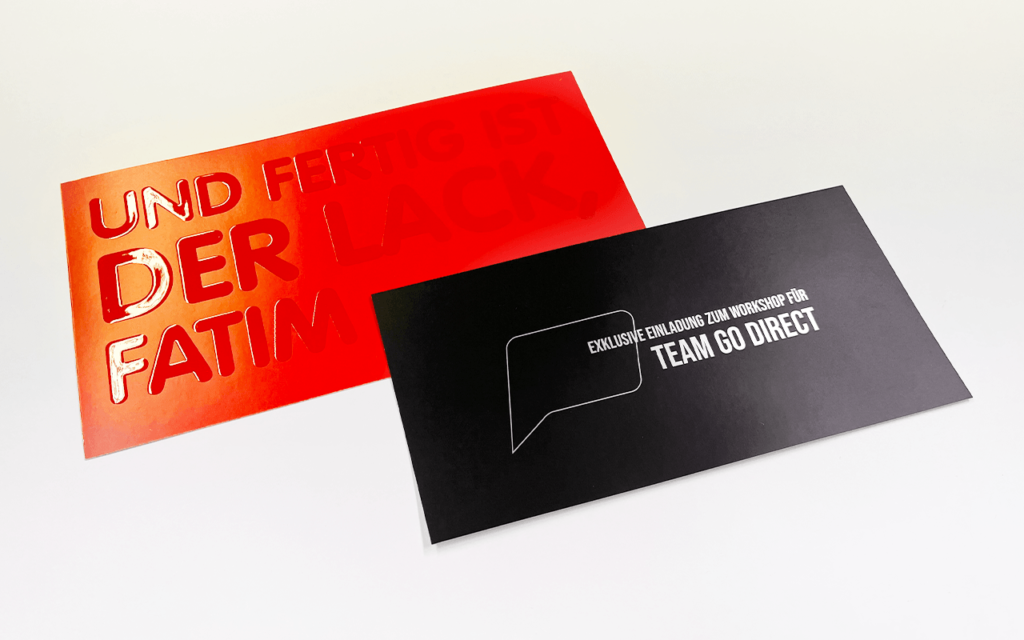 Zwei hochwertige Einladungskarten: Eine rote mit Prägung und eine schwarze mit weißer Schrift.