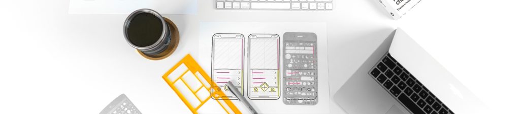 Eine kreative Arbeitsfläche mit handgezeichneten Skizzen von Smartphone-Layouts, Designwerkzeugen und einem Laptop.