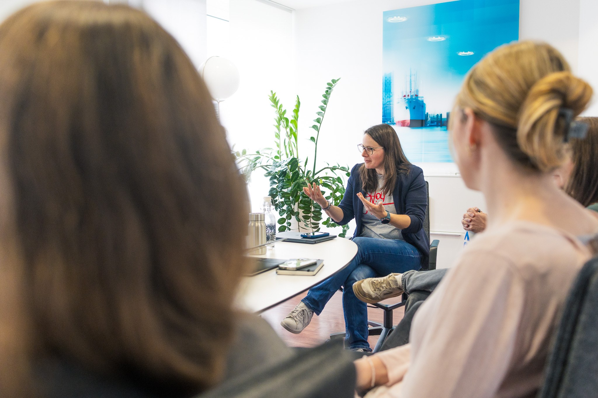 Eine Frau spricht in einer Runde von mehreren Personen. Sie gestikuliert mit den Händen.