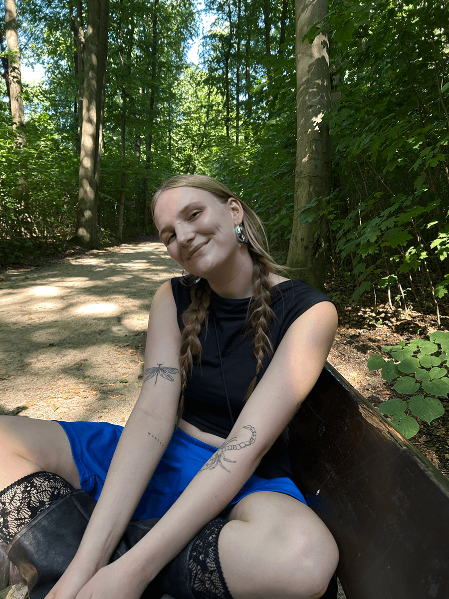 Samira Eschholz sitzt auf einer Bank im Wald.